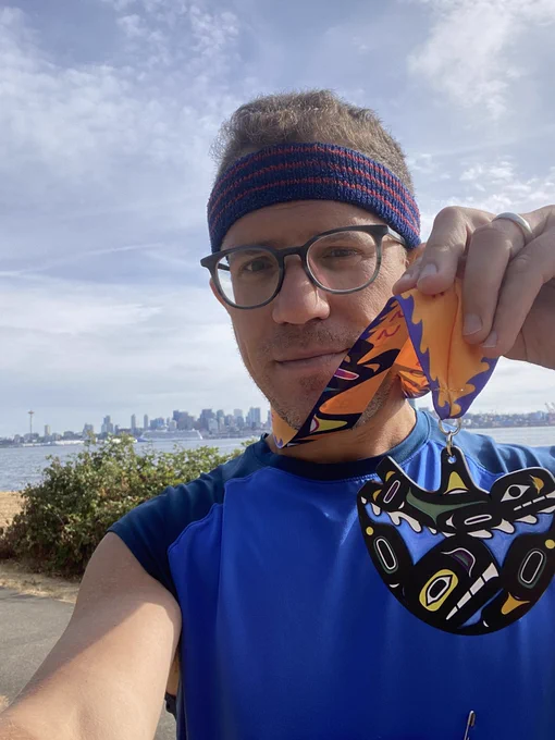 Me holding a race medal in front of the Seattle skyline
