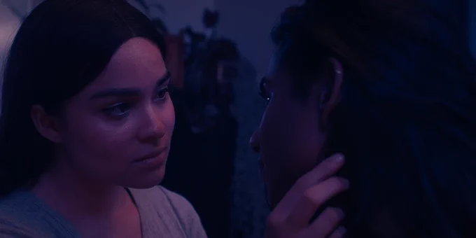 Devery Jacobs caresses the face of Priya Guns. The actors star in a queer love story about two young women — one Iranian and Kanienʼkehá꞉ka, the other Tamil — living in Toronto and dealing with difficult family legacies.