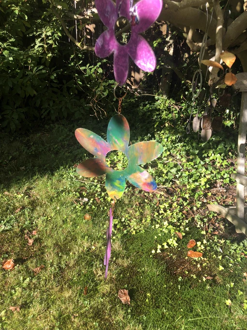 Two purple and a mixed colour flowers chained together hanging down in a garden