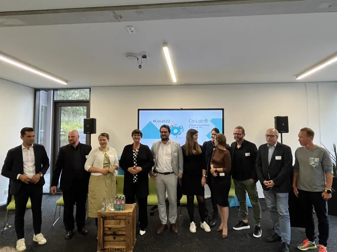 Panelist:innen und Gastgeber des Co:Labs nebeneinander als Gruppe versammelt.