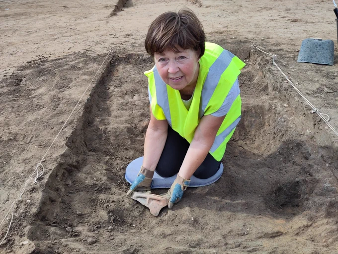 Volunteer holding orange pot sherd with an integrated handle, created by a thick band of clay under the rim