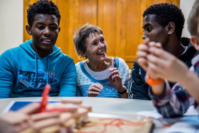 An image of a female volunteer mentor engaging with two male teenagers during a group based mentoring session