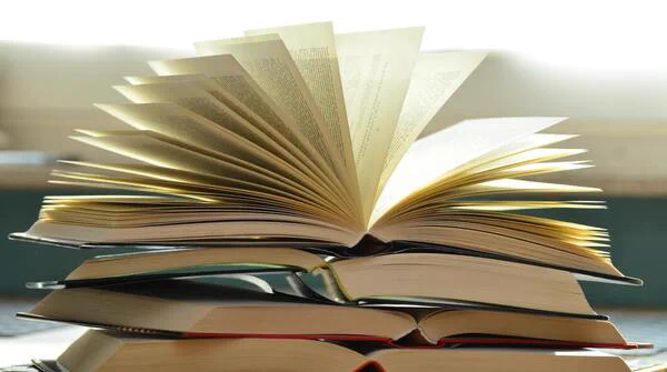 A pile of books with one top that is opened.