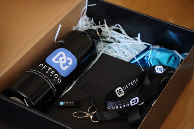 A box containing a Detego Global water bottle, book, USB key, and lanyard.