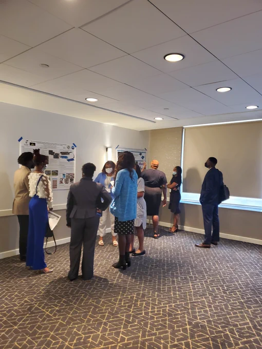 Several people listen to a scientists in front of two research posters 