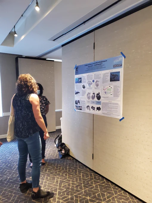 A person looks at a research poster next to a scientist 