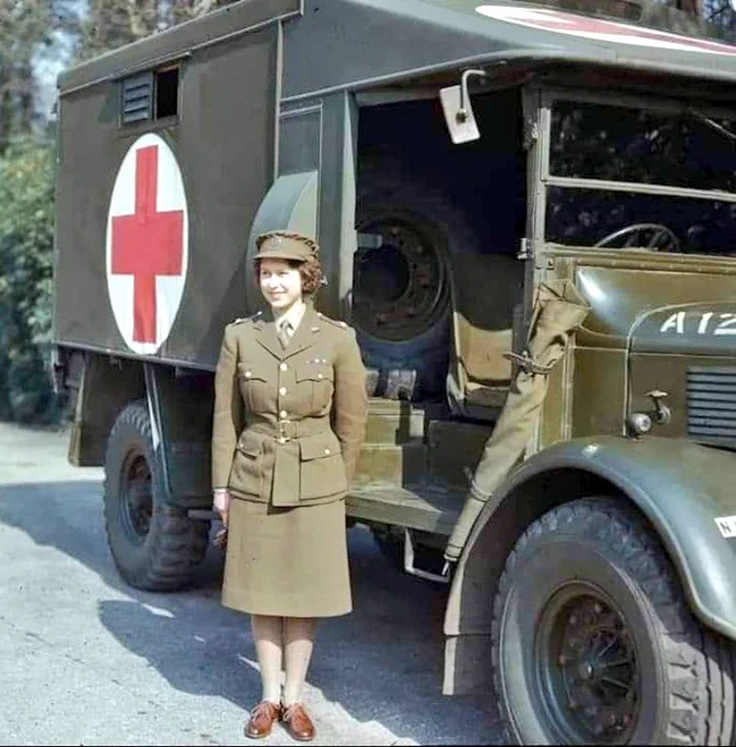 A young queen in military uniform with old green wartime ambulance 
