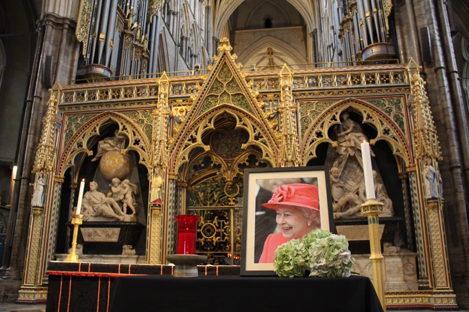 A framed photograph of Queen Elizabeth stands on an altar dressed in black in front of the choir screen in Westminster Abbey