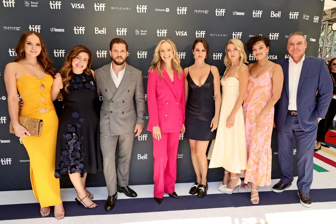 Noémie Merlant, Kit Harington, Bess Wohl, Camila Canó-Flaviá, Meredith Hagner, Alex Saks, Lauren Beveridge, and Brett Beveridge pose in front of a black TIFF backdrop.