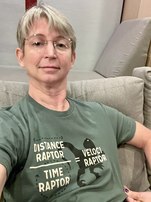 Me, on the couch, wearing a T shirt emblazoned with the text “distance raptor” over a horizontal line, below which “time raptor,” then an equals sign, and “veloci raptor” written on top of the silhouette of a rather demonic looking velociraptor. I bout this shirt to make my teen daughters roll their eyes at me and I am gratified to report success.