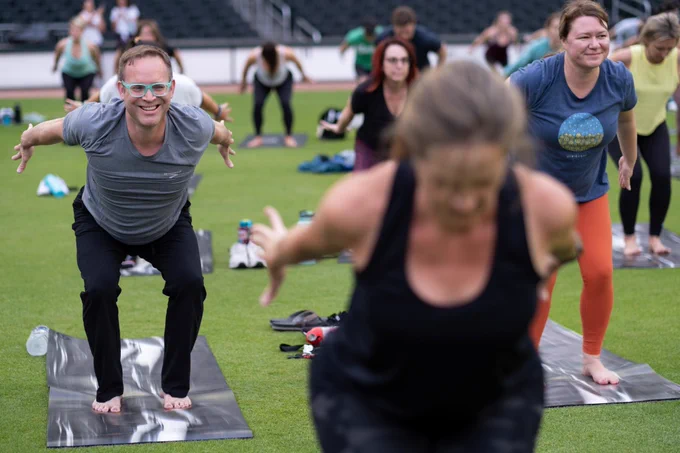 Guests smile during a position in yoga class on field at Truist Park