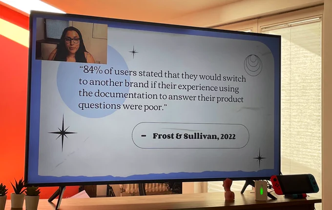 A weird photo of my TV because I didn’t think about taking a screenshot oops. On the TV, Karissa Van Baulen is giving a presentation at Write the Docs Prague 2022. 

The current slide has a statistic from Frost & Sullivan 2023 that reads “84% of users stated that they would switch to another brand if their experience using the documentation to answer their product questions were poor.”