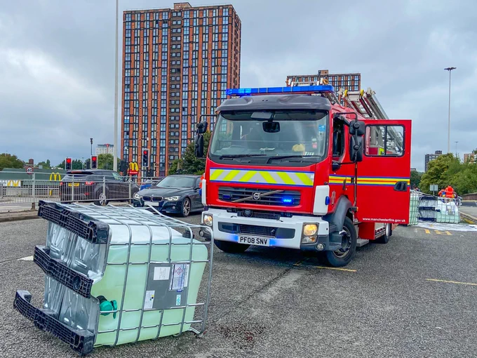 A fire engine with an overturned IBC in front of it