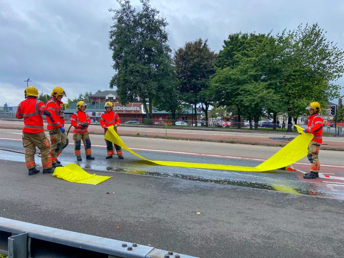 Firefighters install a piece of environmental equipment to stop the spread of the liquid