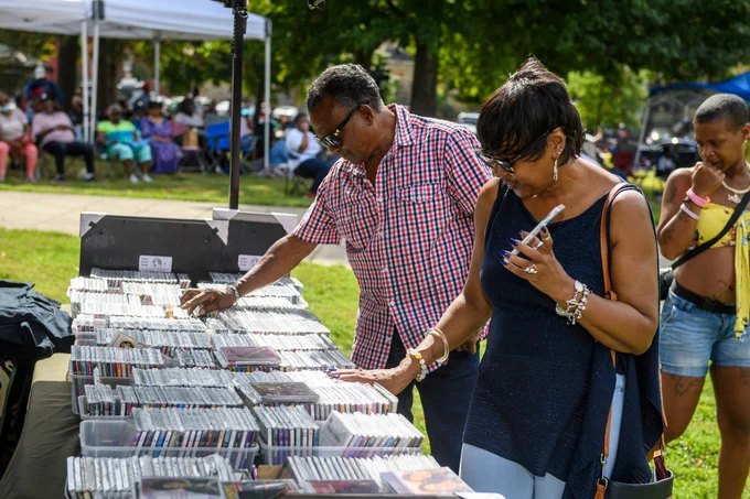 Two people check out a table full of music CDs, sorting through the selection.