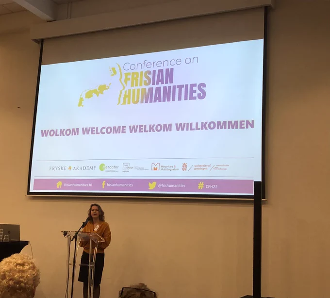 Nelleke on a podium below the logo of the Frisian Humanities Conference, giving the opening speech