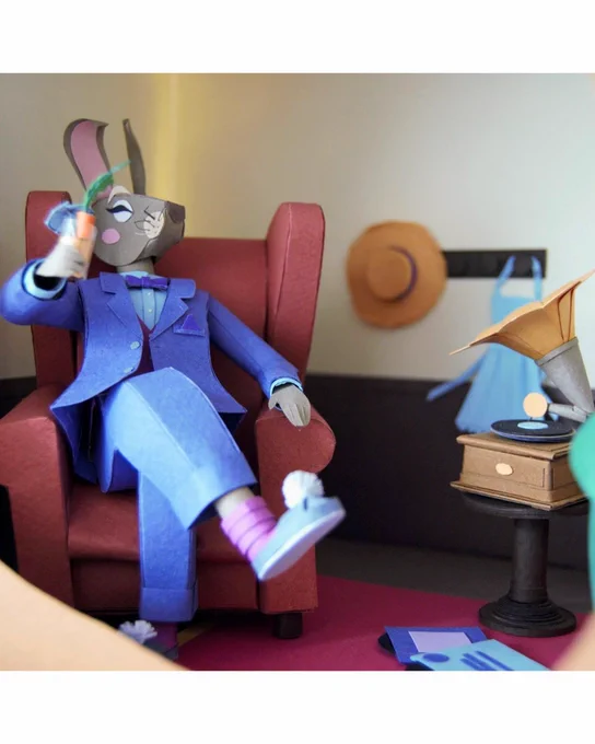 detailed diorama scene made of paper showing rabbit dressed in suit sitting in armchair next to gramophone