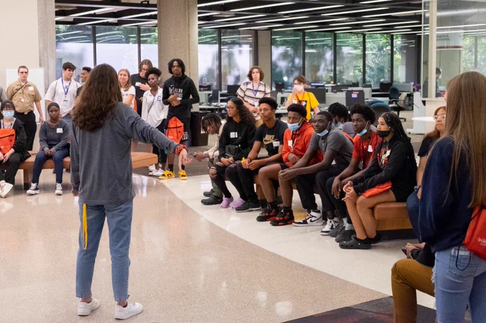 JCPS students listen to a campus tour guide inside a building on the University of Louisville's campus.