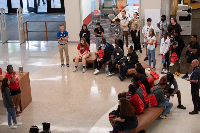 JCPS students listen to two tour guides inside a building on the University of Louisville's campus.