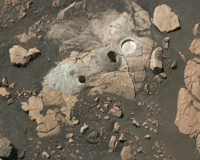 Close-up photo from NASA's Perseverance rover shows a flat rock on Mars, with two drill holes where it has collected rock core samples. Also visible is a shallow patch of rock, about 2 inches (5 cm) in diameter, which has been ground flat by the rover's abrading drill bit.