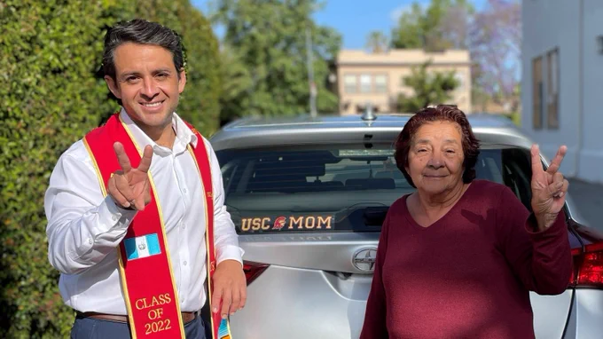 Carlos Lopez and his mom raising FightOn symbol behind a car. 
