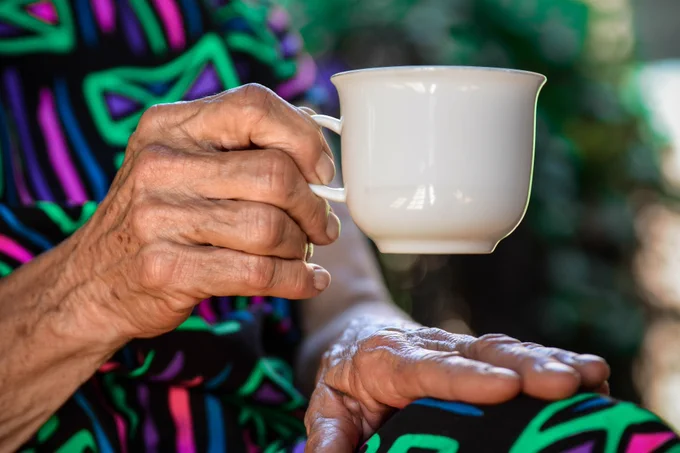 Person holding a white ceramic teacup 