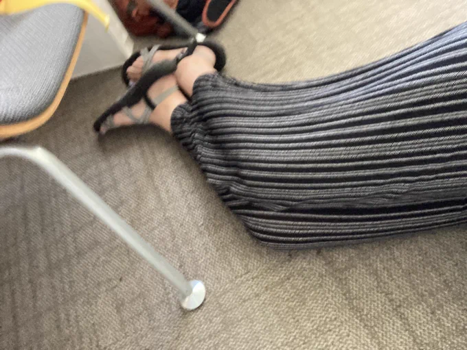 Exhausted parent professor’s legs in black and white striped pants curl on an office floor, lacking a napping couch.