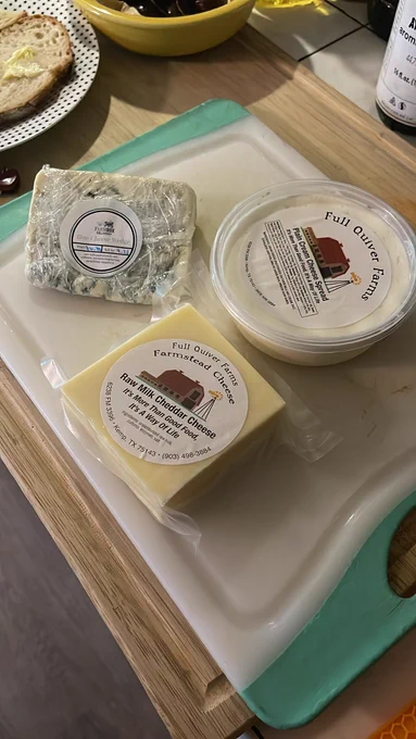 Three wedges of cheese are on a cutting board.
