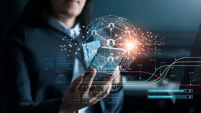A person is holding a phone in their hand and there is a fictional graphic displaying a global with wires and technological webs surrounding the phone. 