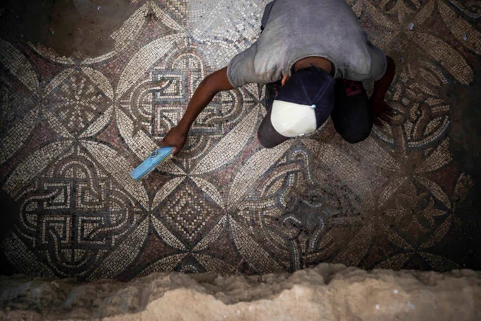 A Palestinian sweeps dust off parts of a Byzantine-era mosaic floor that was uncovered by a farmer in Bureij in central Gaza Strip, Sept. 5, 2022. The man says he stumbled upon it while planting an olive tree last spring and quietly excavated it over several months with his son. Experts say the discovery of the mosaic — which includes 17 well-preserved images of animals and birds — is one of Gaza's greatest archaeological treasures. They say it's drawing attention to the need to protect Gaza's antiquities, which are threatened by a lack of resources and the constant threat of fighting with Israel. Photo: Fatima Shbair - staff, AP