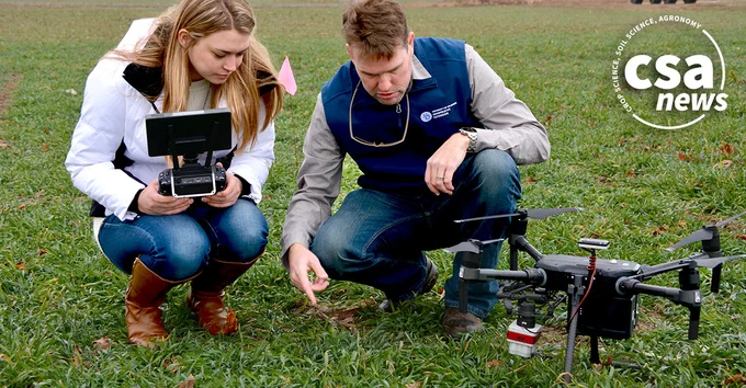 woman and man kneeling in field using drone equipment