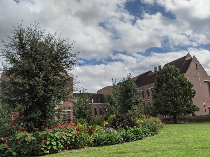 Outdoor photo of the Psychology building at FSU with cloud cover on a perfect fall day. The foreground is rich with vegetation.