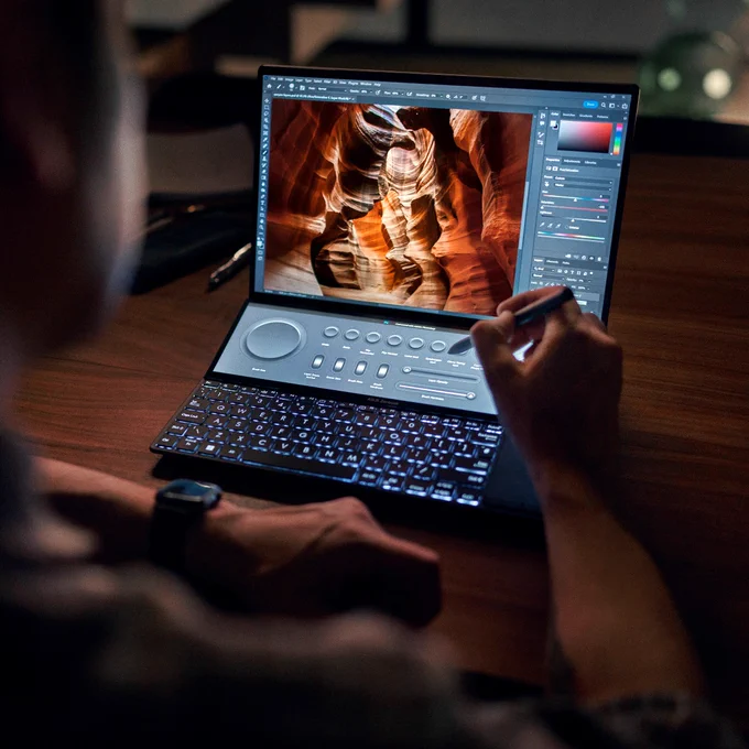 A blurred person is just out of screen on the left/bottom frame with the main focus on the Zenbook Pro 14 Duo OLED