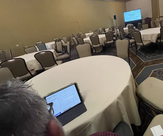 Tom sitting at a table in an empty conference room
