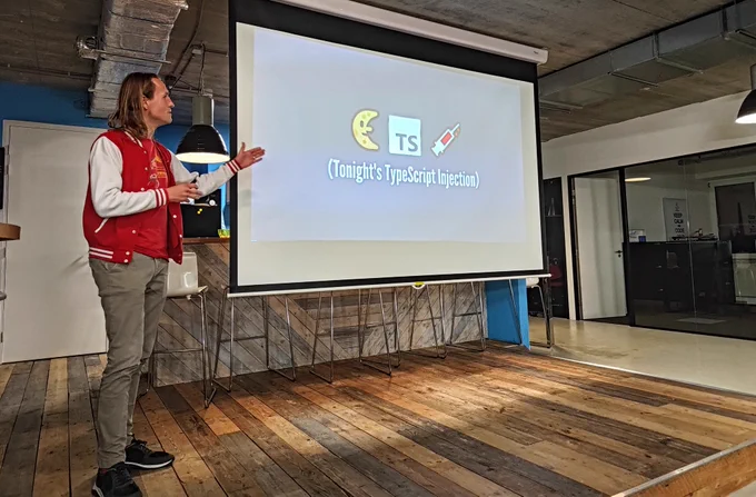 Nico (speaker) pointing at a projected slide saying "Tonight's Typescript Injection"