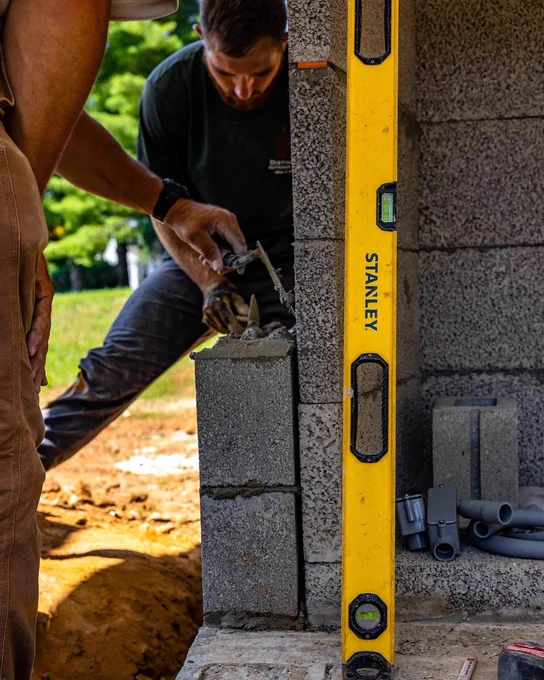 A STANLEY® level resting next to tradesmen laying bricks. 