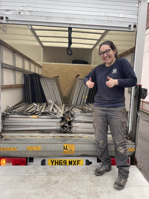 Joanna stands smiling in front of a loaded van full of metal shelving.