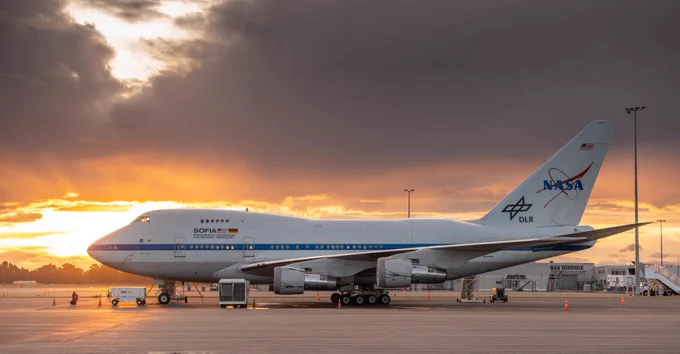 SOFIA is on the ground in front of an orange sunset. 