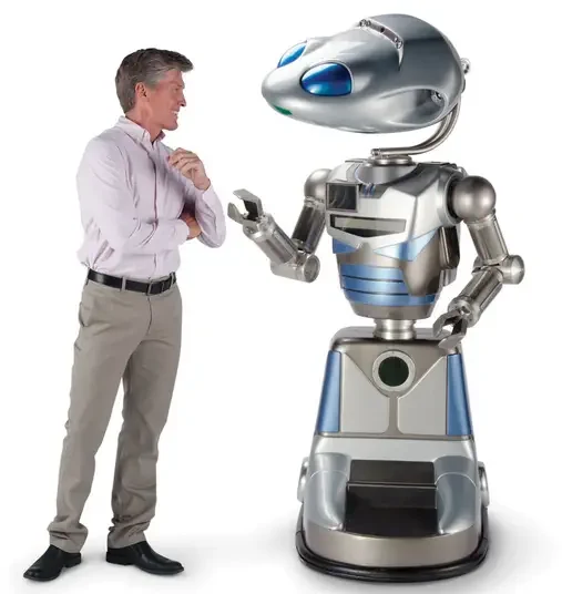 A man conversing with a goofy looking robot. The robot does not have legs but is humanoid and has a huge head.