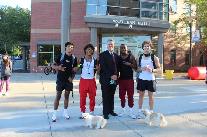 President Maloney (center) with students and his rescue dogs Daisy and Anabelle accompany him during his evening walk through campus at  Quadfest.