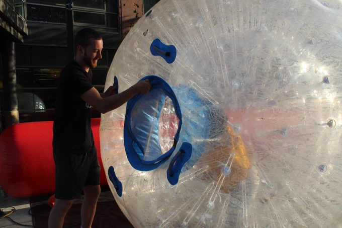 Student (in yellow) climbs into inflatable bowling ball to experience what it feels like to gently roll into inflatable candle pins as a "human bowling ball." Some students were thumbs up while others gave the experience a hard pass. 