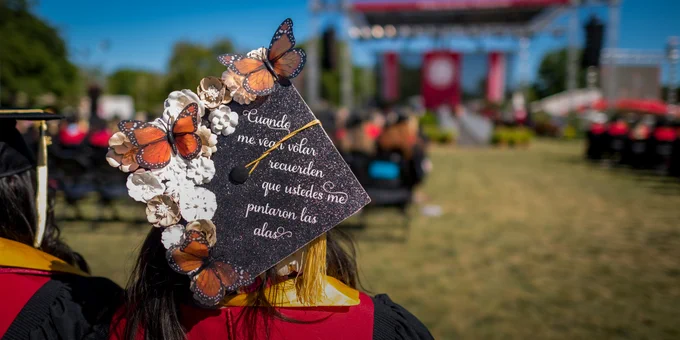 Decorated graduation cap with butterflies and Spanish words stating "Cuando me vean volar recuerden que ustedes me pintaron las alas," which translates to "When you see me fly, remember that you all painted me wings." 