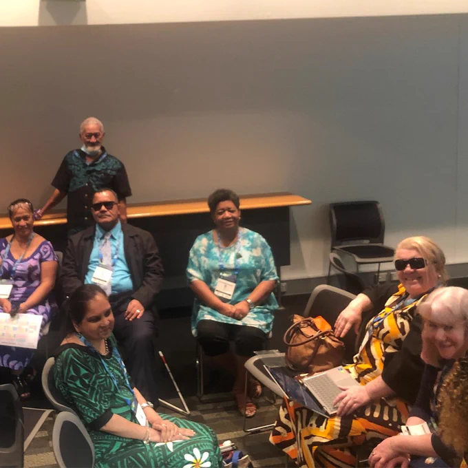 A group of people sitting in a room smiling. They are staff from the PDF Secretariat meeting with Disabled Persons Organisations delegates from Vanuatu, the Cook Islands, Fiji and Australia.