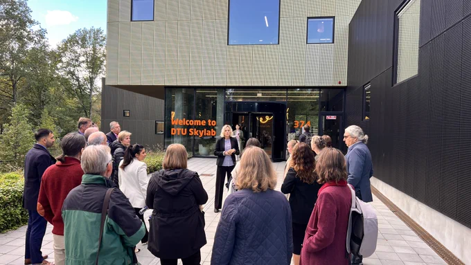 ANE workshop delegates in front of the DTU Skylab Entrance door - a sign on the building says "Welcome to DTU Skylab".