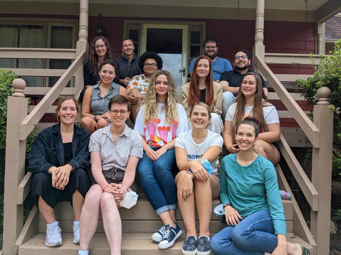 A group of people posing for a photo on the steps of a house.