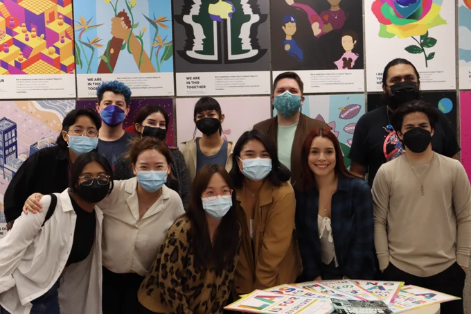 Professor Vernon and his students smiling proudly in front of their artworks.