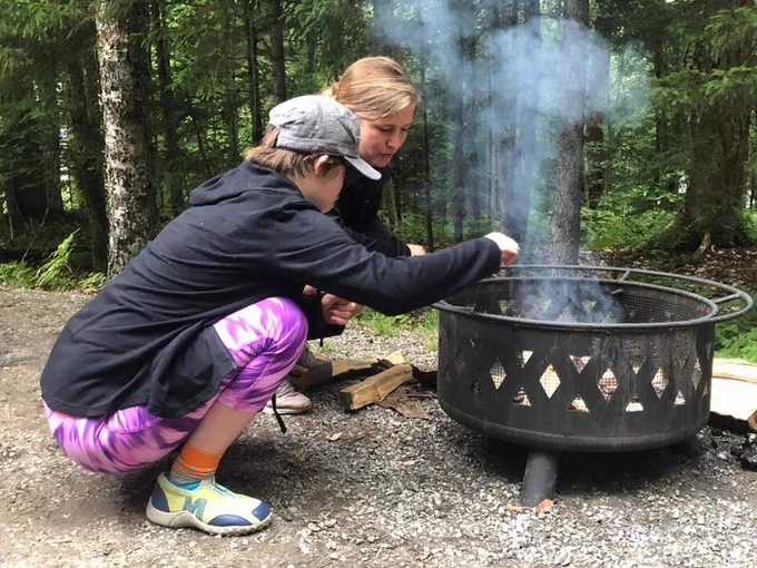 Young Leader, Ace, a white disabled person, works with Ally, Kelly, a white non-disabled woman, to build a fire.