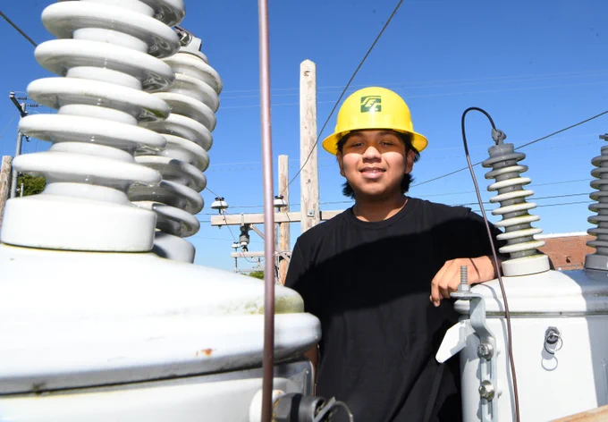 student in hard hat outside by power lines