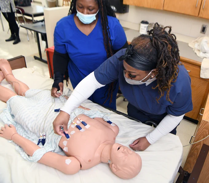 two students working on a dummy patient