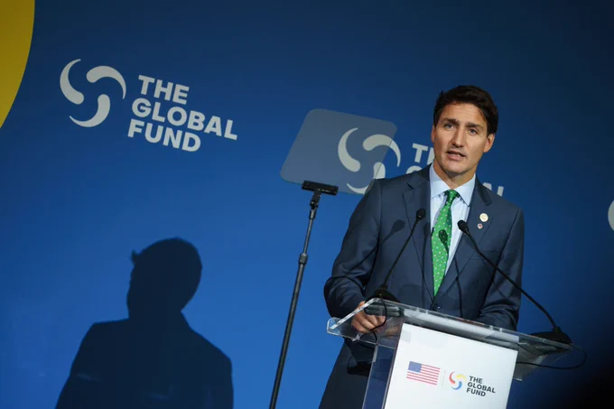 Le premier ministre Justin Trudeau est debout et parle derrière un lutrin. On peut voir derrière lui une bannière sur laquelle est inscrit "Global Citizen".